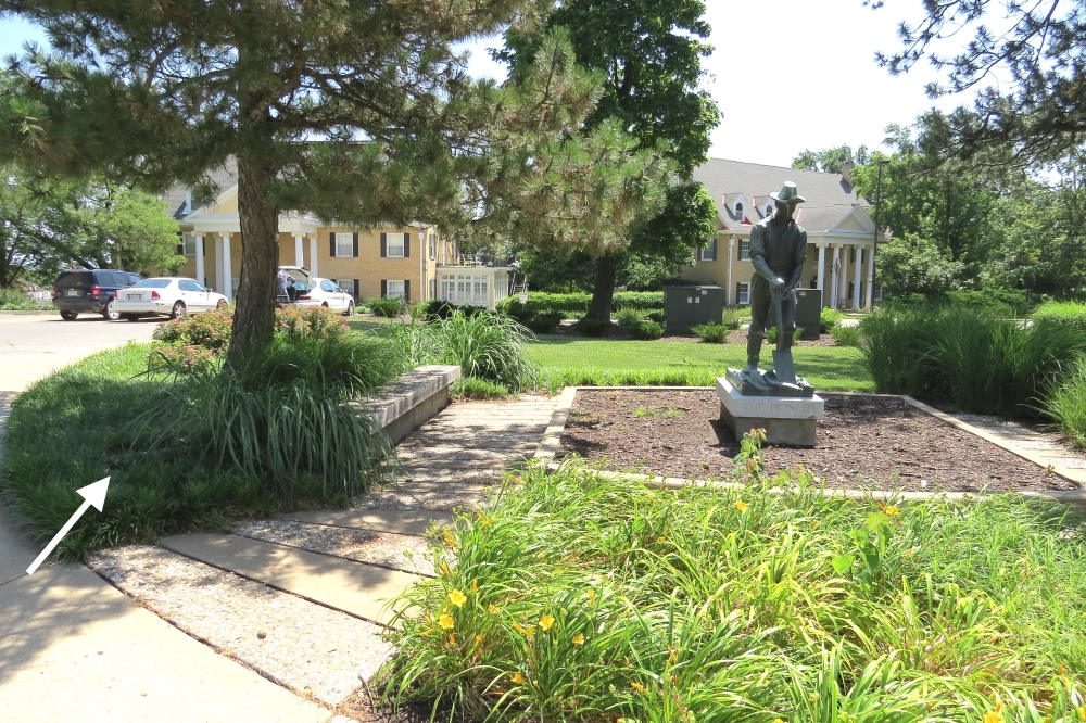 Statue of The Pioneer with white arrow showing location of marker